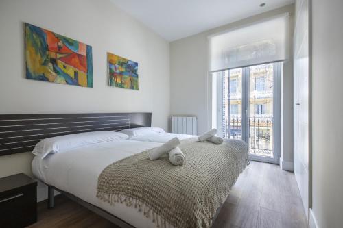 un dormitorio con una cama con dos animales de peluche en Urbieta Korner - Local Rentss, en San Sebastián
