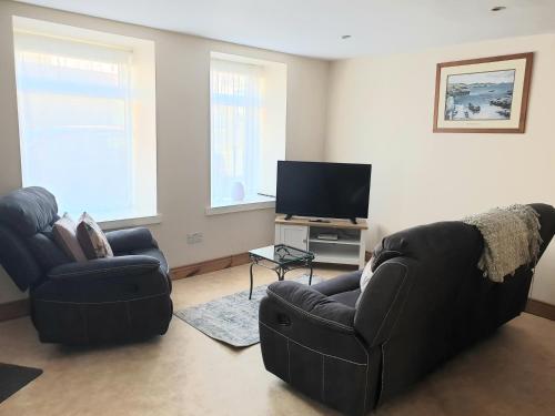 a living room with two couches and a flat screen tv at Teach Eoin in Dingle