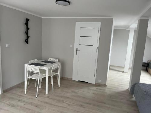 a white room with a table and chairs and a door at Pokoje na Górce in Rajgród
