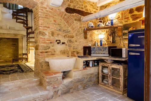 a stone kitchen with a sink and a refrigerator at Casa Pereta in Magliano in Toscana