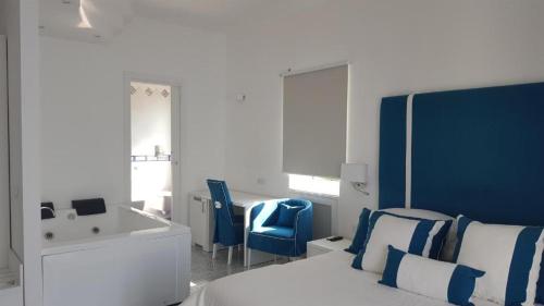 a white and blue bedroom with a bed and chairs at Hotel Bristol in Vietri
