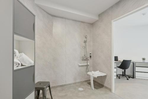 a bathroom with a shower and a chair and a desk at All Suites Noisy Le Grand in Noisy-le-Grand