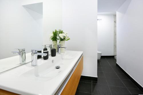 a white bathroom with a sink and a mirror at Coast Guard Apartment in Faro