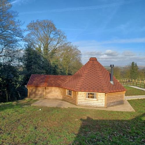 una pequeña casa con techo rojo en un campo en Antler Lodge, en Rushton Spencer