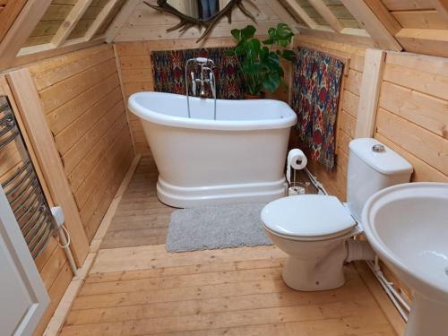 a bathroom with a tub and a toilet and a sink at Antler Lodge in Rushton Spencer