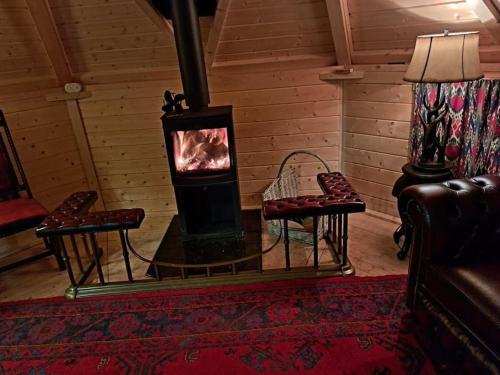 a wood stove in a room with two chairs at Antler Lodge in Rushton Spencer