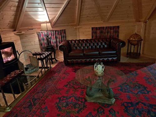 a living room with a leather couch and a table at Antler Lodge in Rushton Spencer