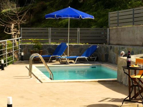 a pool with chairs and an umbrella and a table at Aretousa by PosarelliVillas in Dhrakóna