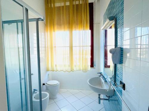 La salle de bains est pourvue d'un lavabo, de toilettes et d'une fenêtre. dans l'établissement Regina Beach Holiday Apartments, à Tirrenia