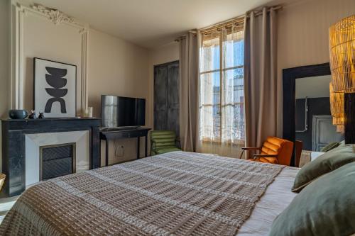 a bedroom with a bed and a fireplace and a television at La Maison de Lyna - Suites de charme intra-muros avec parking & autonomie in Aigues-Mortes