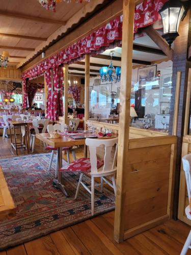 un restaurant avec des tables en bois et des chaises blanches dans l'établissement Le Trésor des Vosges Appartement spacieux et lumineux 80m2 - jeux arcades - idéal famille 4 à 6 personnes, à Gérardmer