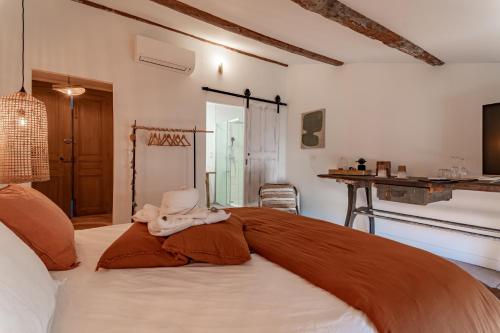 a bedroom with a large bed with an orange blanket at La Maison de Lyna - Suites de charme intra-muros avec parking & autonomie in Aigues-Mortes
