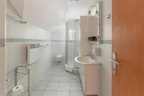 Baño blanco con lavabo y aseo en Apartma Metka, en Medvode