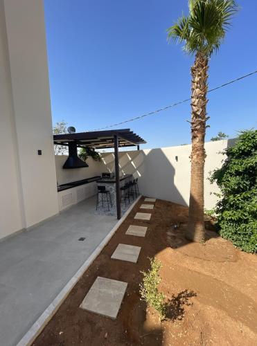 a patio with a table and a palm tree at Zerø Føur DeadSea in Sowayma