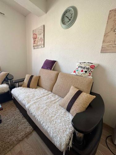 a living room with a couch and a clock on the wall at Apartman Zaga in Trebinje