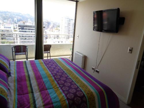 1 dormitorio con 1 cama y TV de pantalla plana en Delpino Propiedades Palmas del Mar, en Viña del Mar