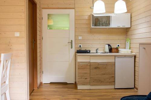 uma cozinha com um lavatório e uma porta em Domki latonafali em Dąbki