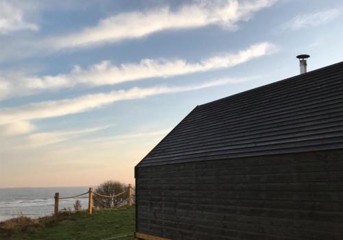 a roof of a building with the ocean in the background at St Hilda Beach Hut in Alnmouth