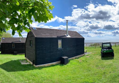 a small black building in the grass with a jeep at St Hilda Beach Hut in Alnmouth