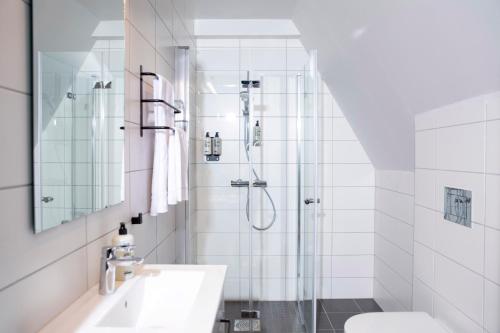 a white bathroom with a shower and a sink at Bob W Sentralen in Oslo