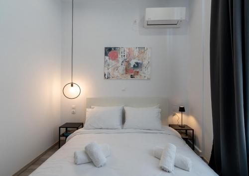 1 dormitorio con 1 cama blanca y 2 almohadas en Central Suites Aegina 1, en Aegina Town