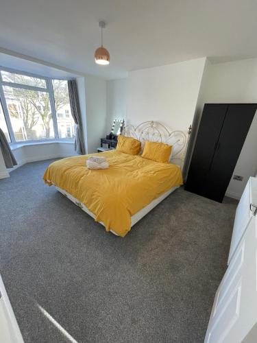 1 dormitorio con 1 cama grande con colcha amarilla en Englehurst Mews flat 2, en Buxton