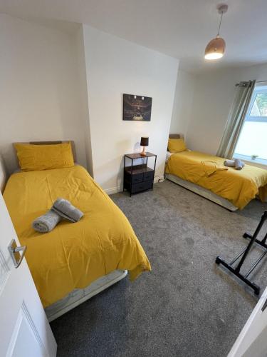 two beds in a room with yellow sheets at Englehurst Mews flat 2 in Buxton