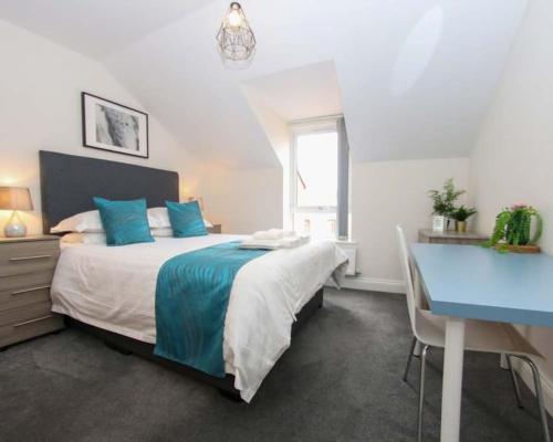 een slaapkamer met een groot bed en een blauw bureau bij Luxe Living Guest House-Sleeps 6 -Family Friendly-Private Parking-Wifi-City-Beach in Swansea