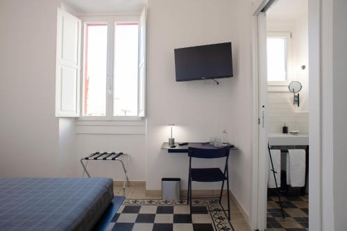 een slaapkamer met een bed, een bureau en een televisie bij Al Dio Bes in Cagliari