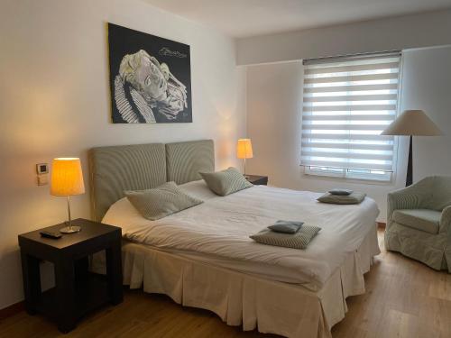 une chambre avec un grand lit et une chaise dans l'établissement Arthur Properties Rue d'Antibes, à Cannes