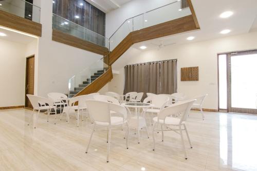 Un comedor con sillas blancas y una mesa. en FabHotel Sky Lark Farm, en Ludhiana