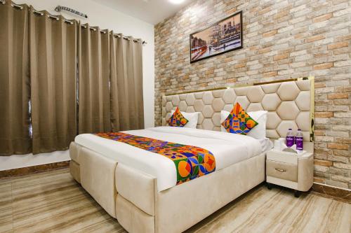 1 dormitorio con 1 cama grande y pared de ladrillo en FabHotel Sky Lark Farm en Ludhiana