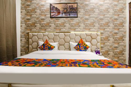 1 cama en un dormitorio con pared de ladrillo en FabHotel Sky Lark Farm en Ludhiana