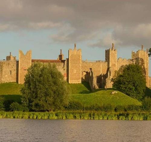 a castle sitting on a hill next to a body of water at Potters Brook in Framlingham