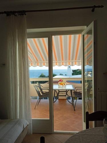 a room with a glass door leading to a patio with a table at Apartmani Vesna in Lun