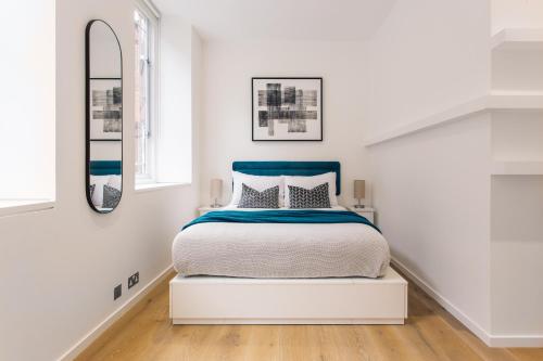 a white bedroom with a bed and a mirror at 2 Bed 2 Bath Apartment Off Regent Street in London