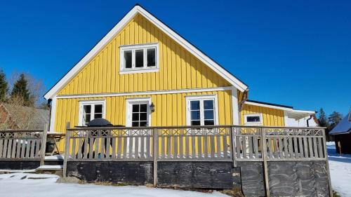 uma casa amarela com uma cerca na neve em ELGGÅRDEN em Torup