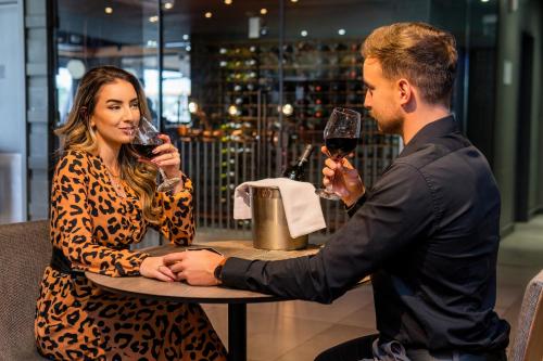a man and a woman sitting at a table with wine glasses at Novotel Criciuma in Criciúma
