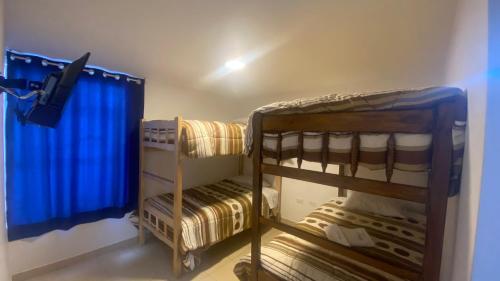 two bunk beds in a room with blue curtains at La Pascana Hospedaje in Cajamarca