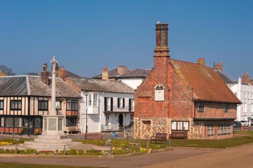 an old brick building with a tower on a street at Potters Brook in Framlingham