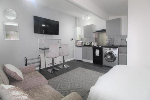 a living room with a couch and a kitchen at Studio 2 min walk to Upton Park Station in London