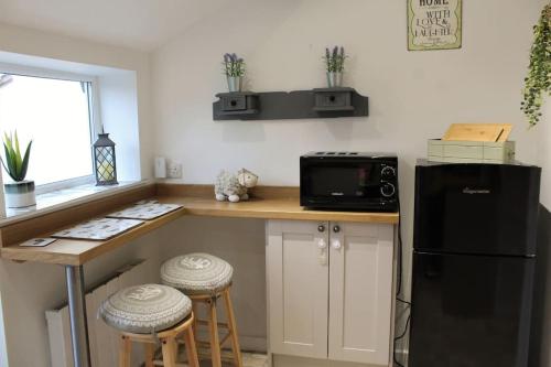 a kitchen with a black refrigerator and a counter with stools at Bumblebee Cottage nestled in stunning countryside. in Barrowford