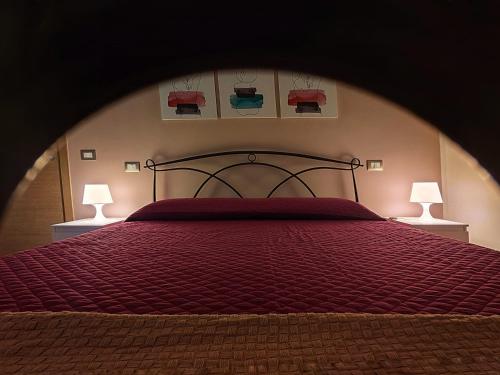 テレーゼにあるb&b Telesillaのベッドルーム1室(赤い掛け布団、ランプ2つ付)