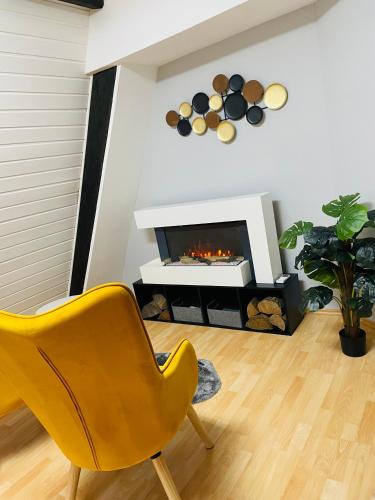 ein Wohnzimmer mit einem gelben Stuhl und einem Kamin in der Unterkunft Ferienwohnung Hotel Glockenhof in Eltville