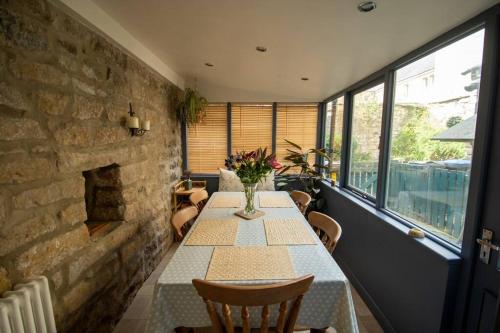 a dining room with a table and a brick wall at Characterful 2 bed cottage in excellent location in Baslow