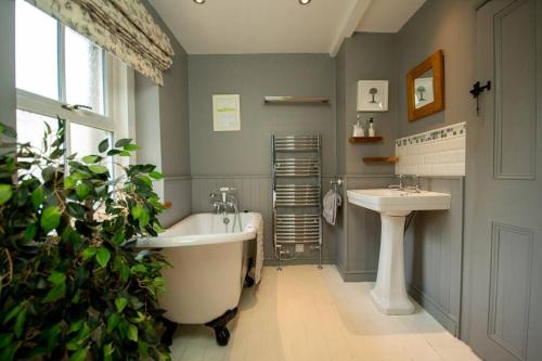 a bathroom with a bath tub and a sink at Characterful 2 bed cottage in excellent location in Baslow