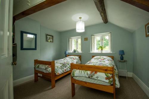 a bedroom with two beds and two windows at Characterful 2 bed cottage in excellent location in Baslow