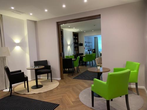 a waiting room with green chairs and tables at Behringers City Hotel Nürnberg in Nuremberg