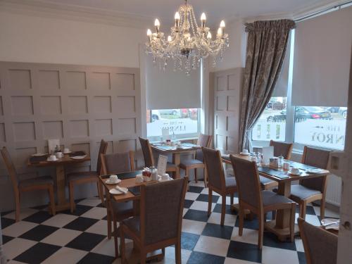 a dining room with tables and chairs and a chandelier at Linroy Guest House in Skegness