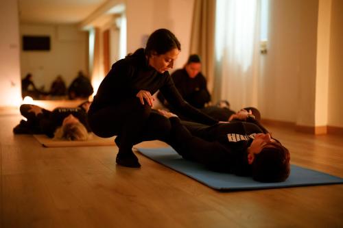 a woman helping a man laying on the floor in a yoga class at ARIA - Villa di Campagna in Montecorvino Rovella